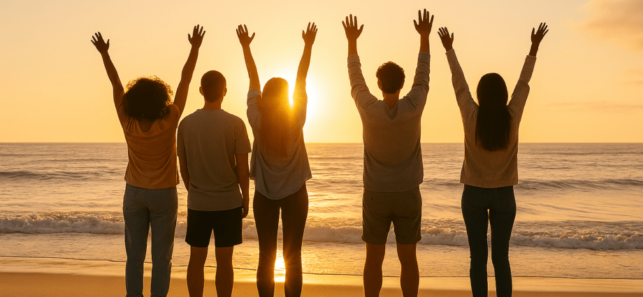 Motivation: Fünf Menschen am Strand beim Sonnenaufgang mit erhobenen Armen – motivierende Gruppenstimmung